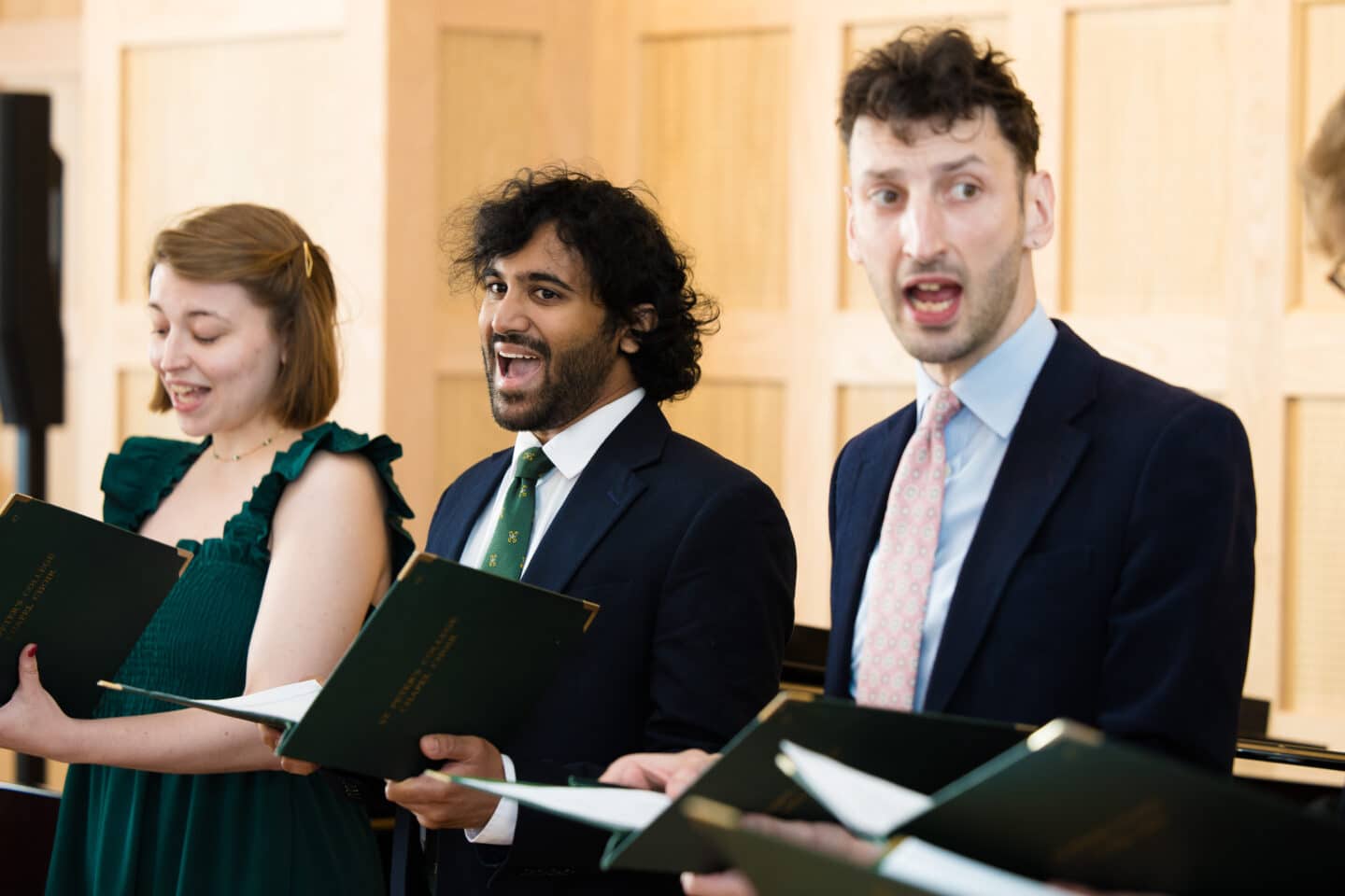 Three singers performing in a wood-panelled room.