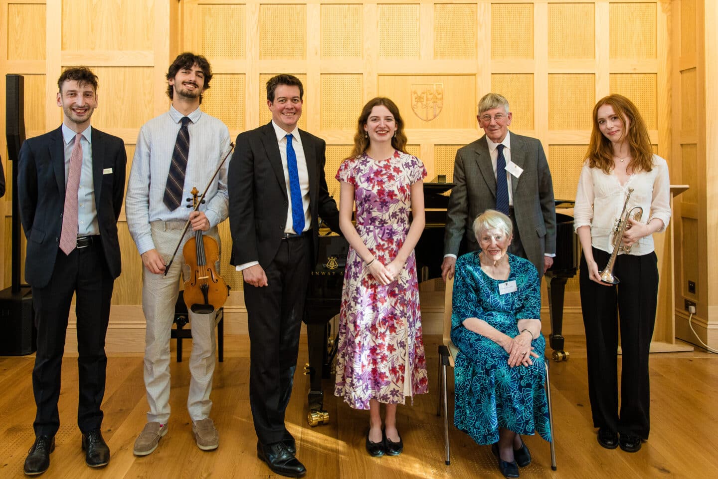 A group of people standing by a piano together.