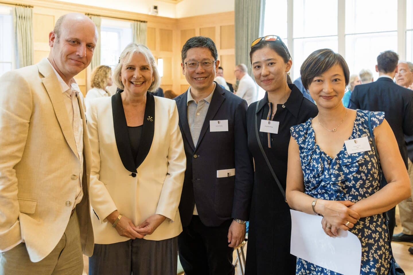 a group of five people smiling indoors in semi-formal attire.