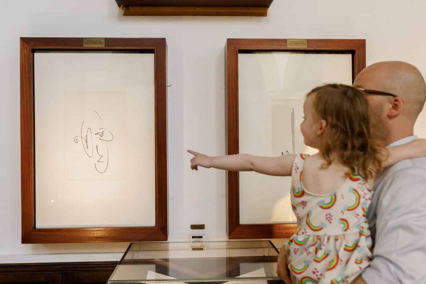 A man and a child look at an artwork at an art exhibition