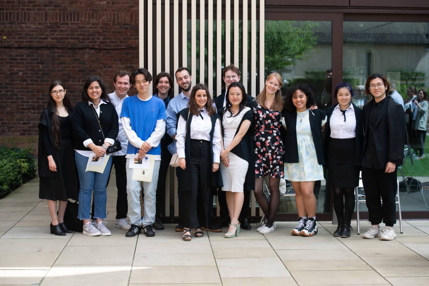 A group of students posing together outside a modern building
