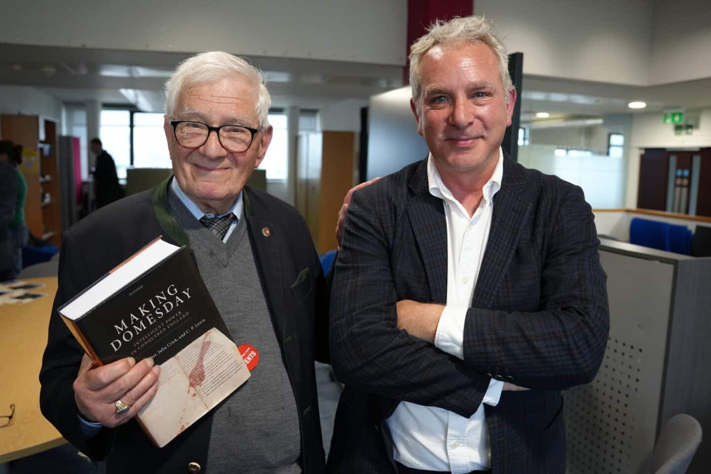 Two men smiling and standing indoors