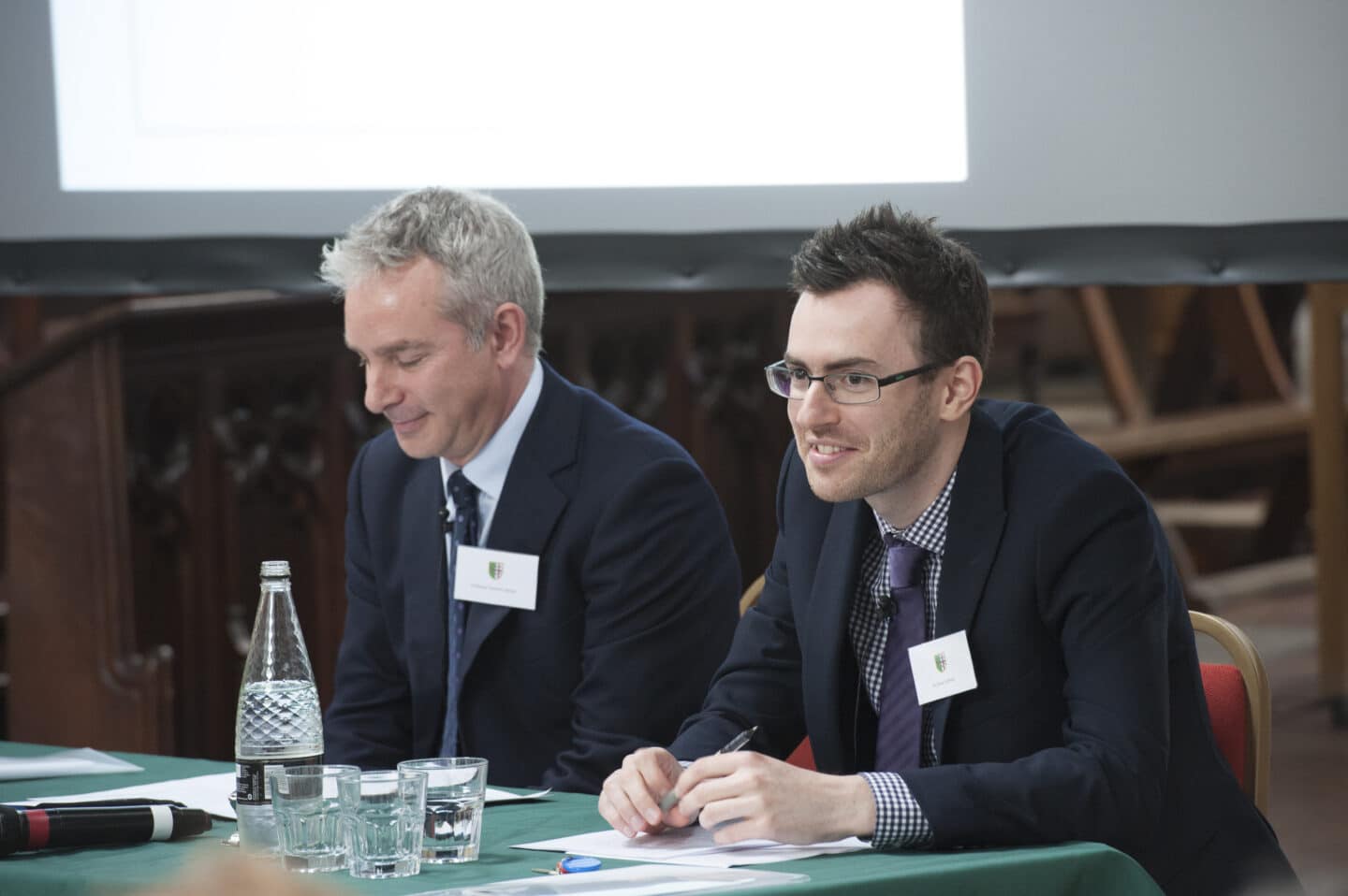 Two men sat at a table at a conference.