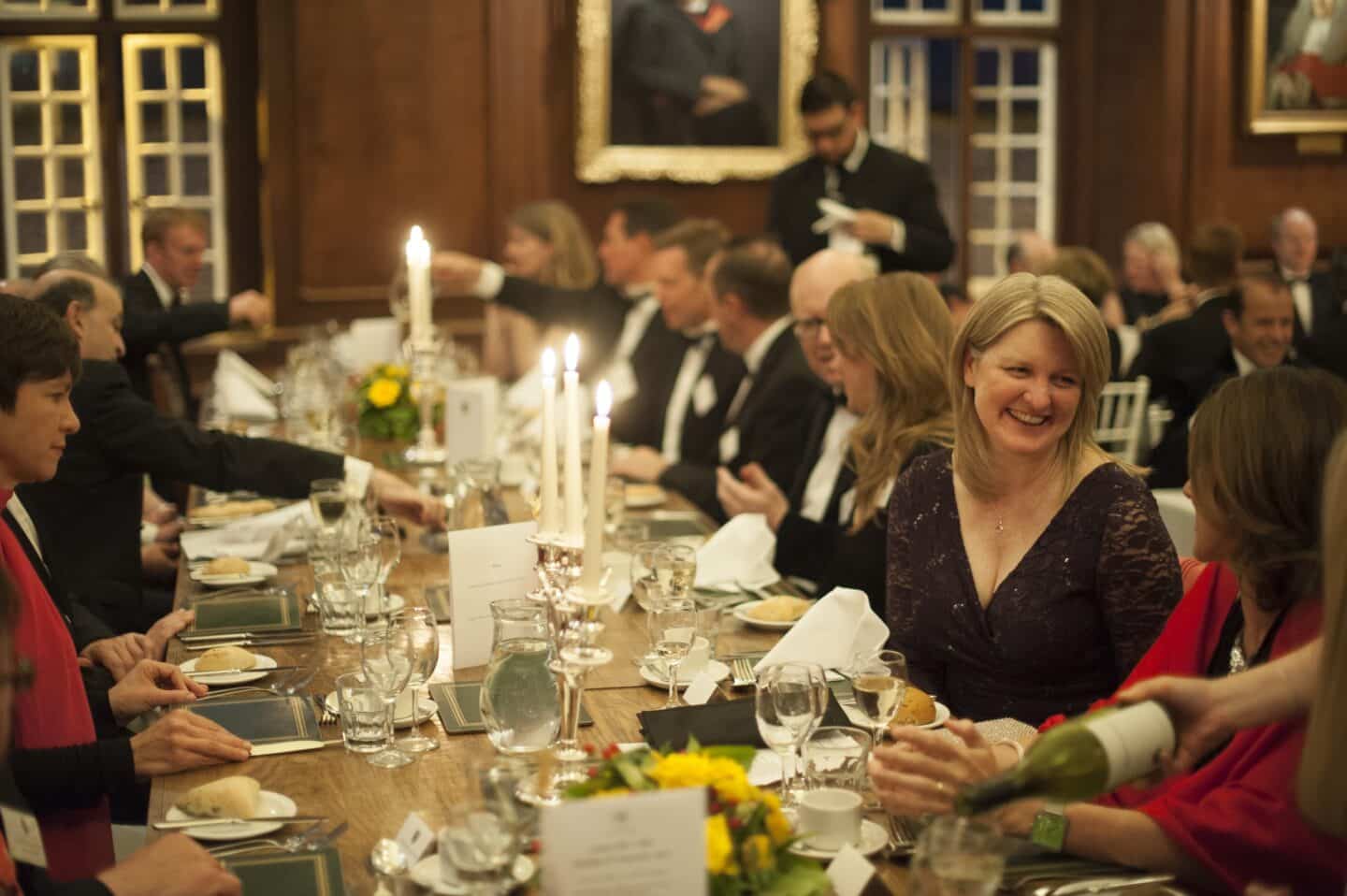 A group of people enjoying a formal dinner inside a candlelit hall