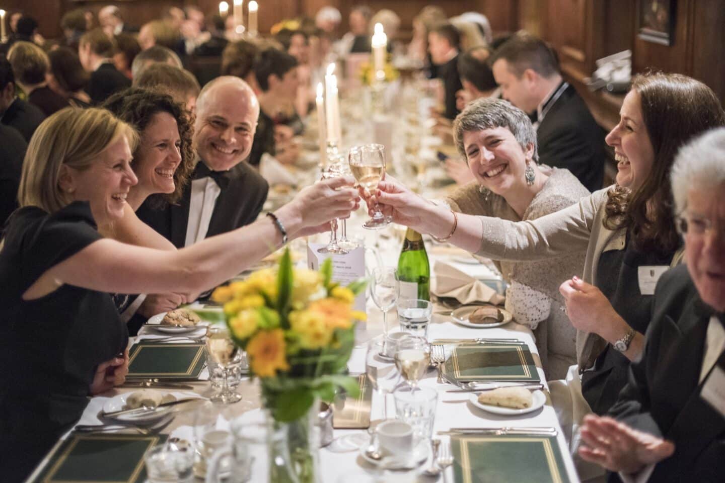 a group of people smiling and giving a toast at a formal dinner