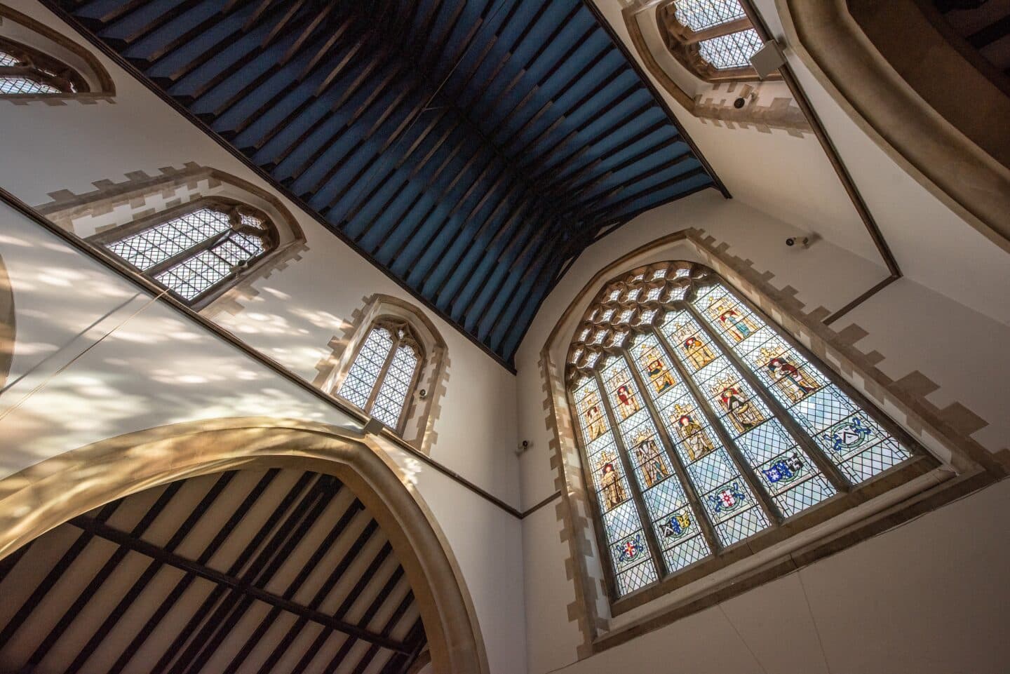 image of a chapel interior including a blue ceiling and a large stained glass window