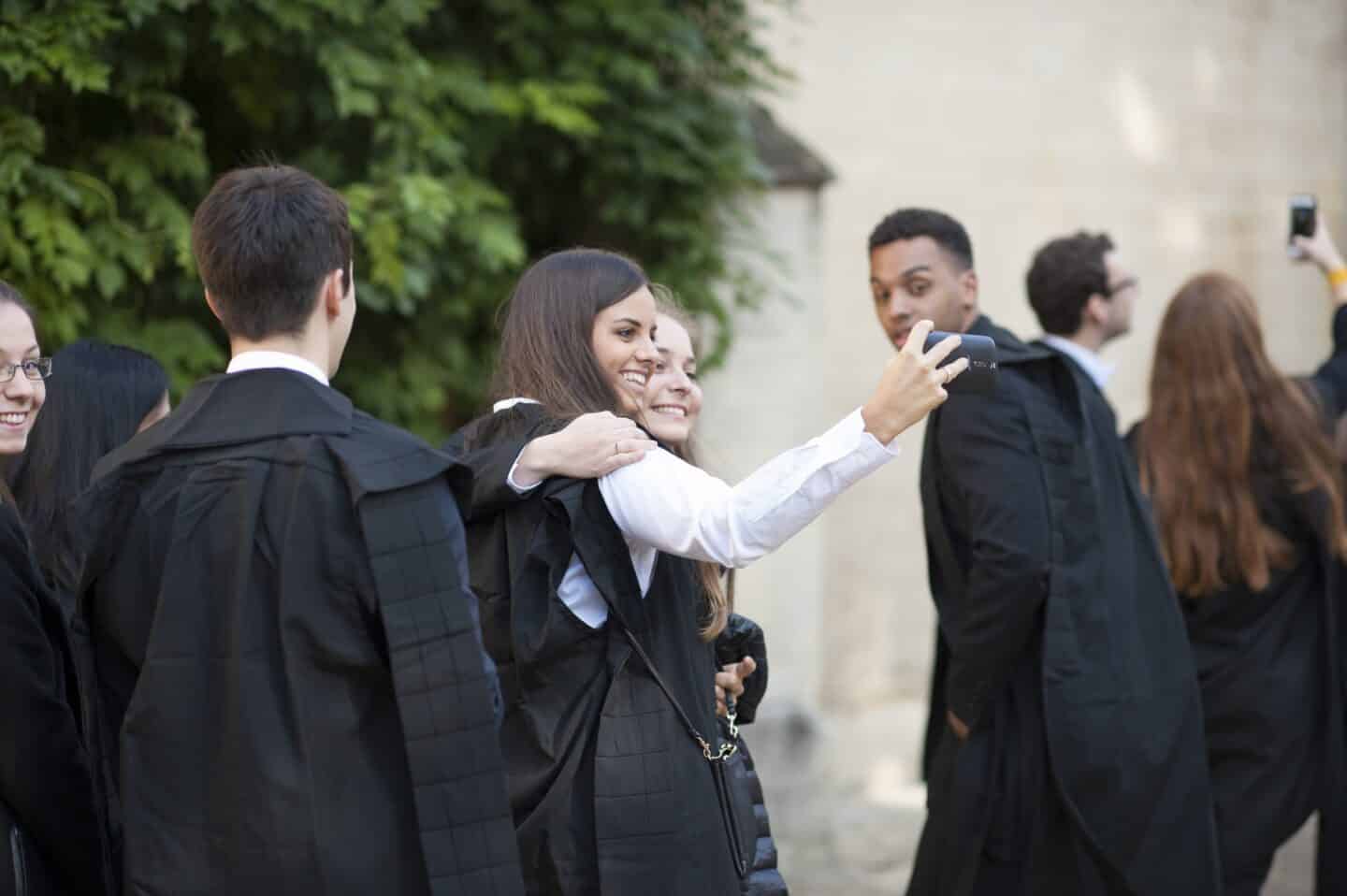 Students wearing academic gowns and taking a selfie