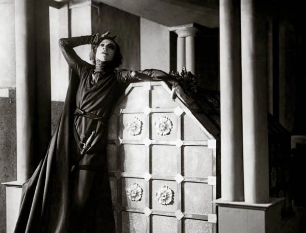Asta Nielsen in a costume leaning against a carved wooden panel