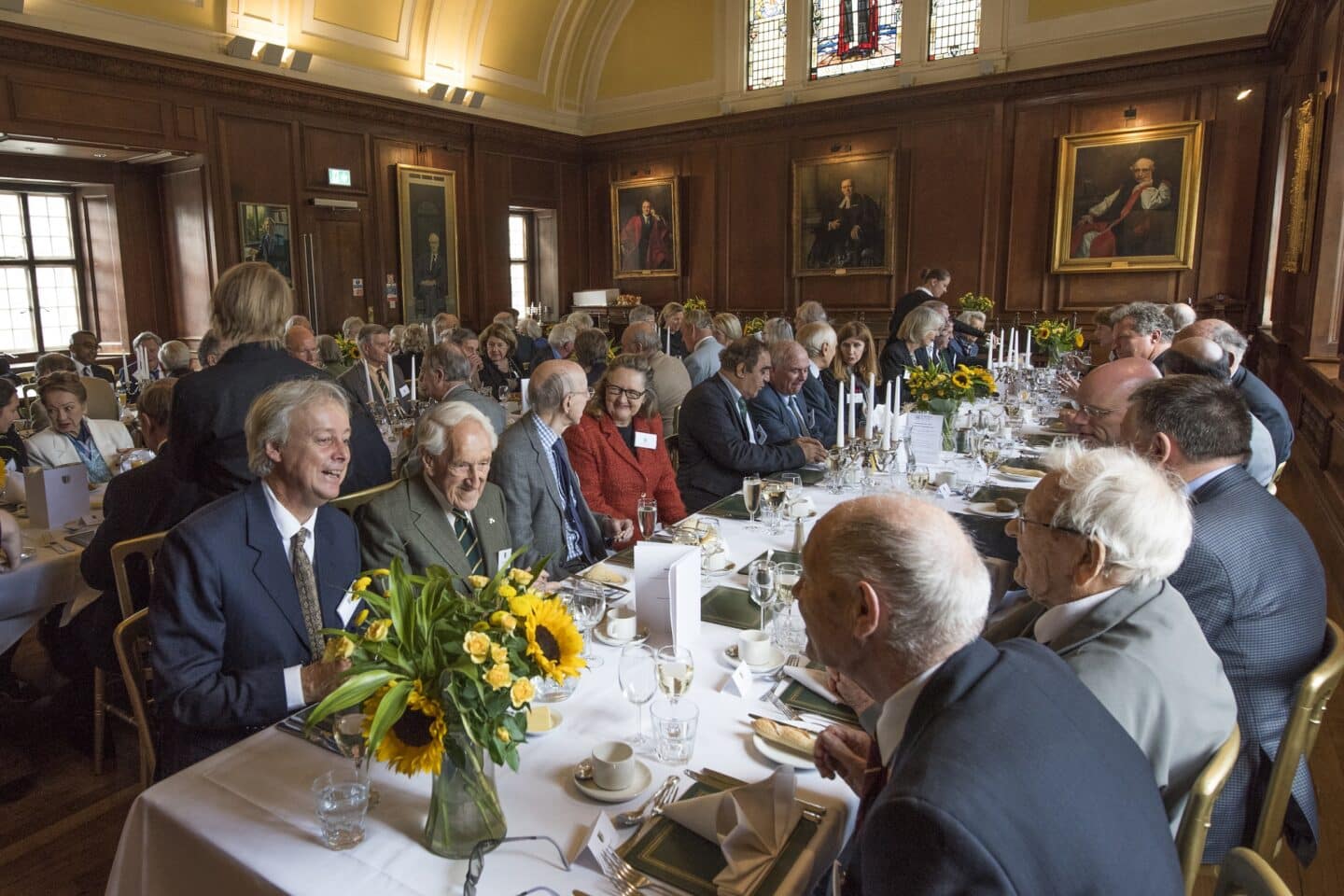 A large gathering of people enjoying a formal dinner in a large hall