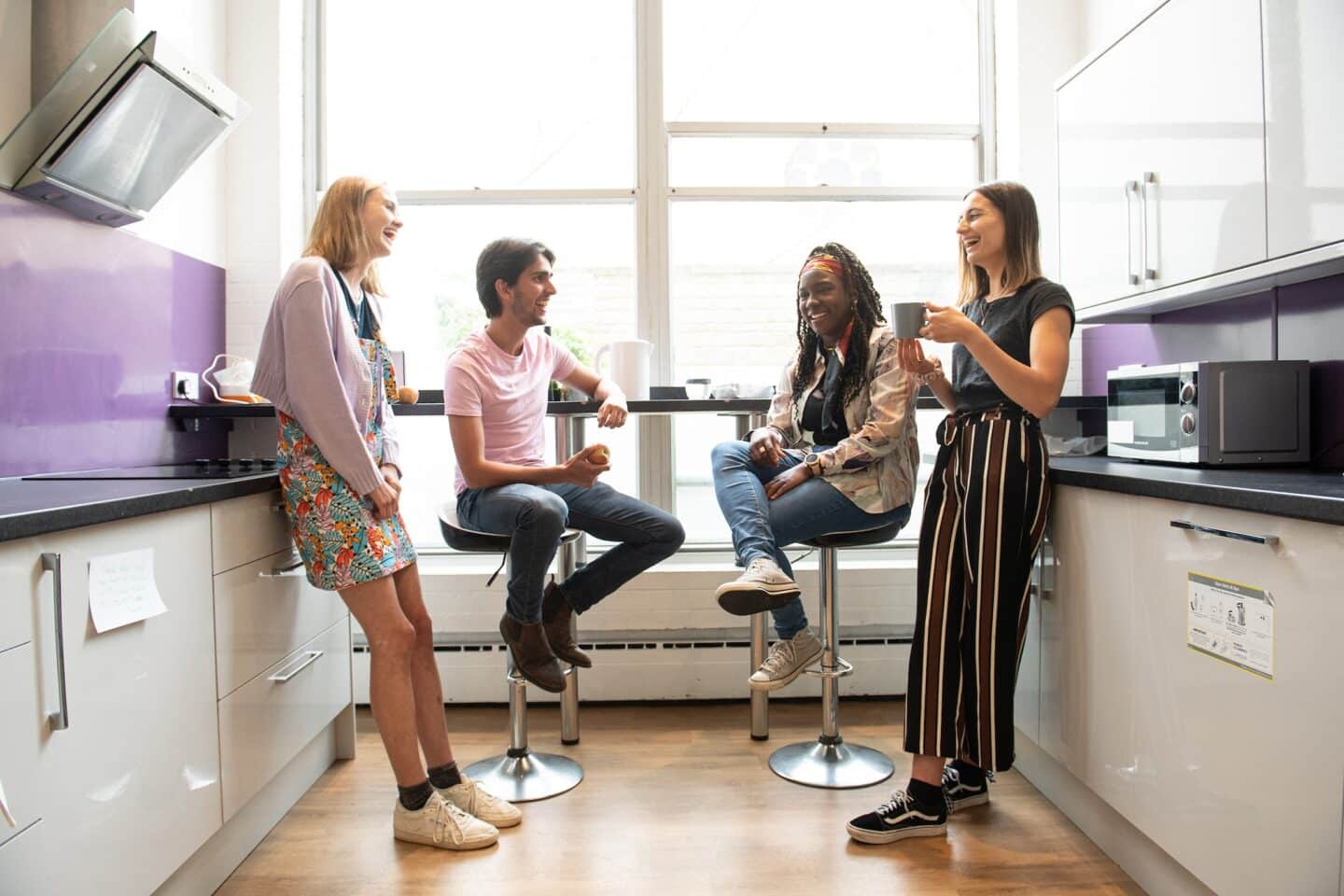 four students smiling in a kitchen