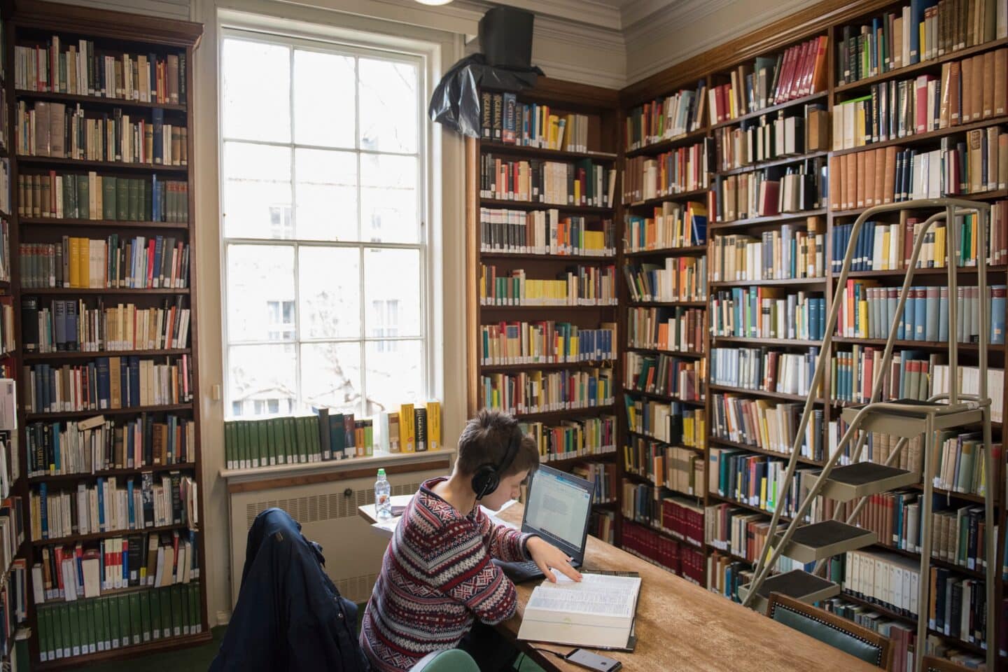 a student in a library with a computer and dictionary