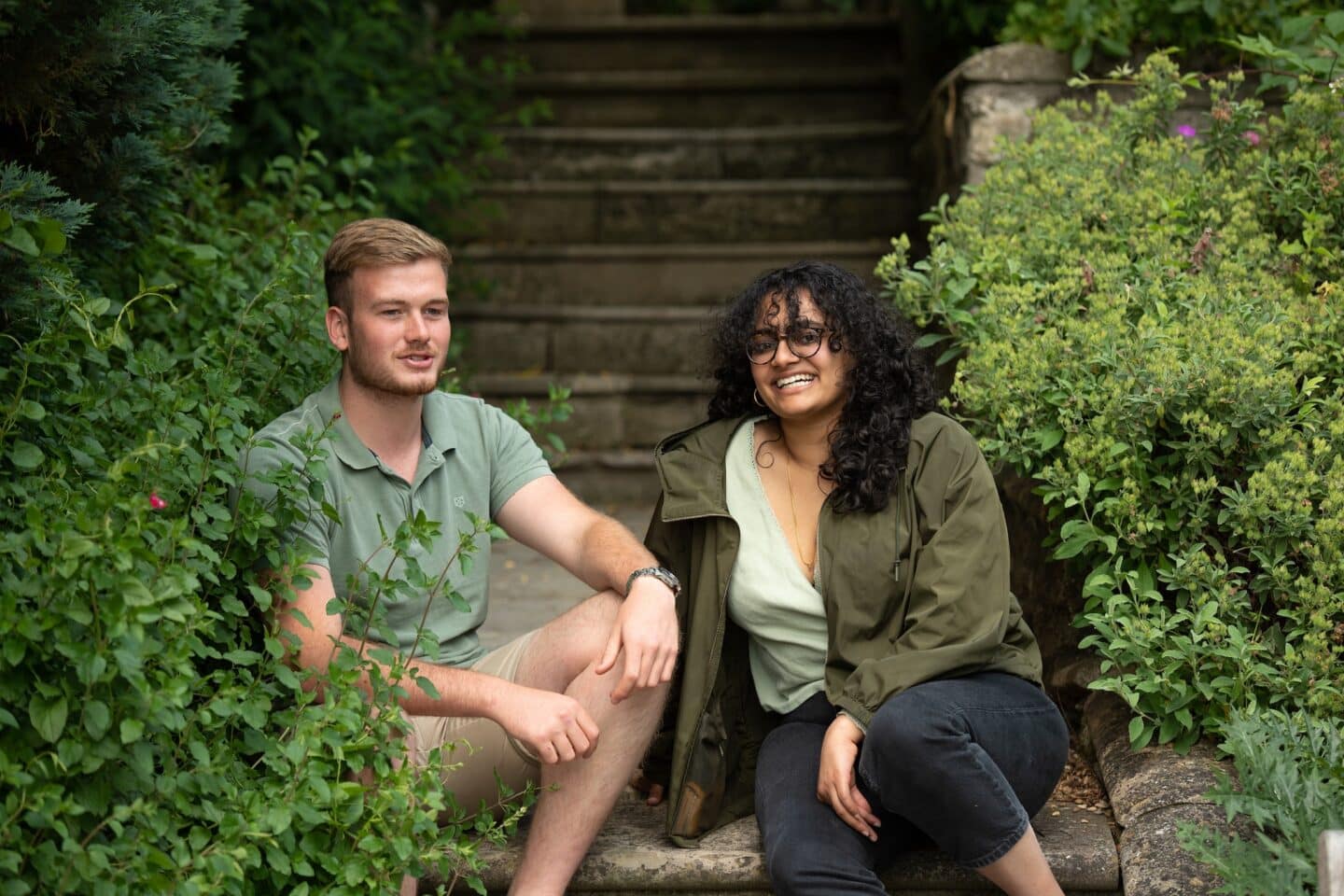 two students sitting on a staircase in a garden