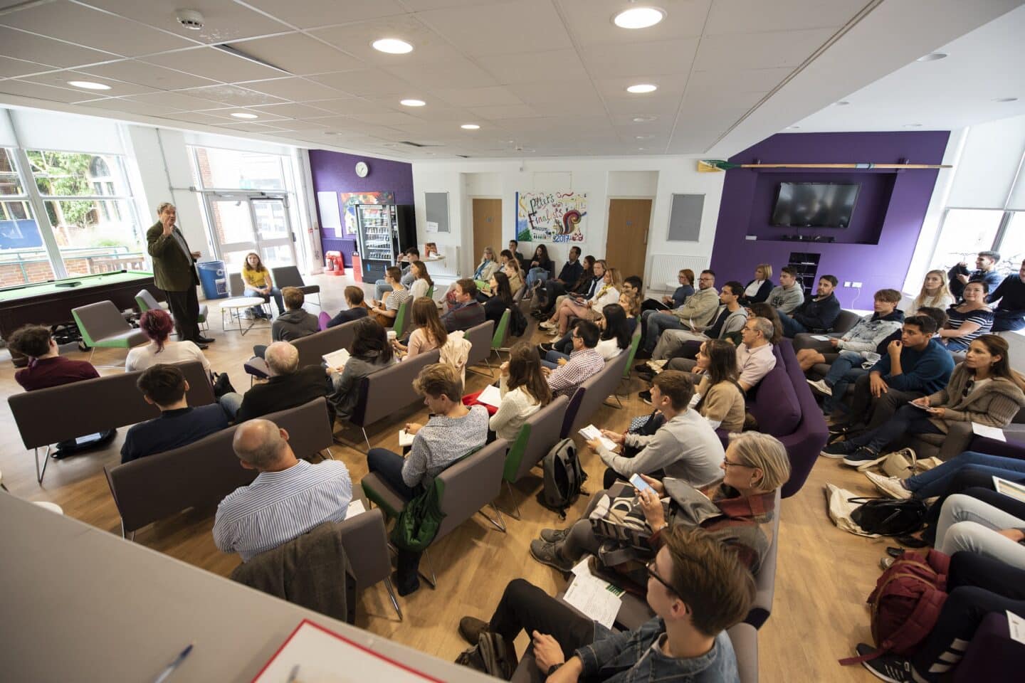 A large gathering of people listening to a speaker