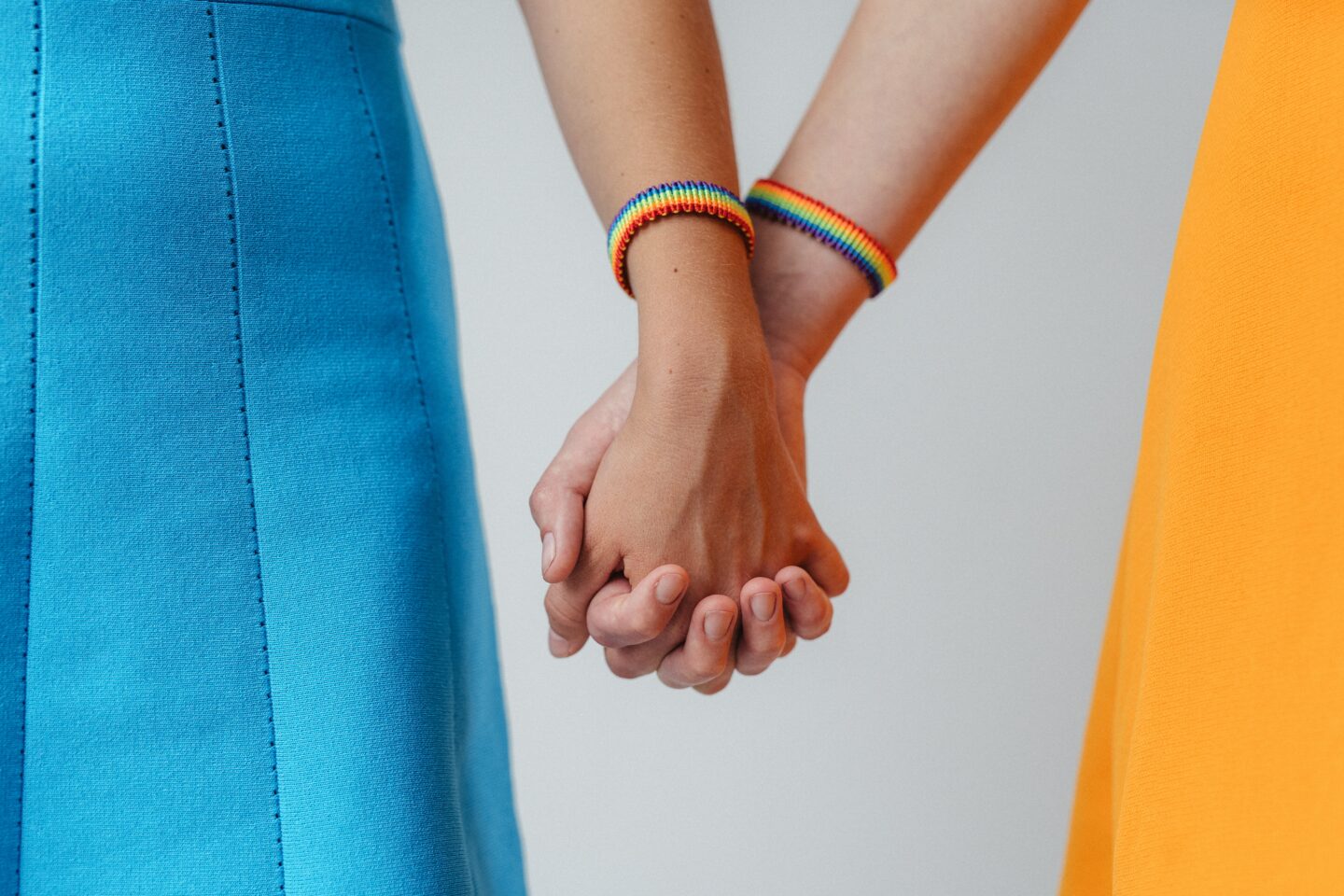 two people wearing rainbow bracelets and holding hands