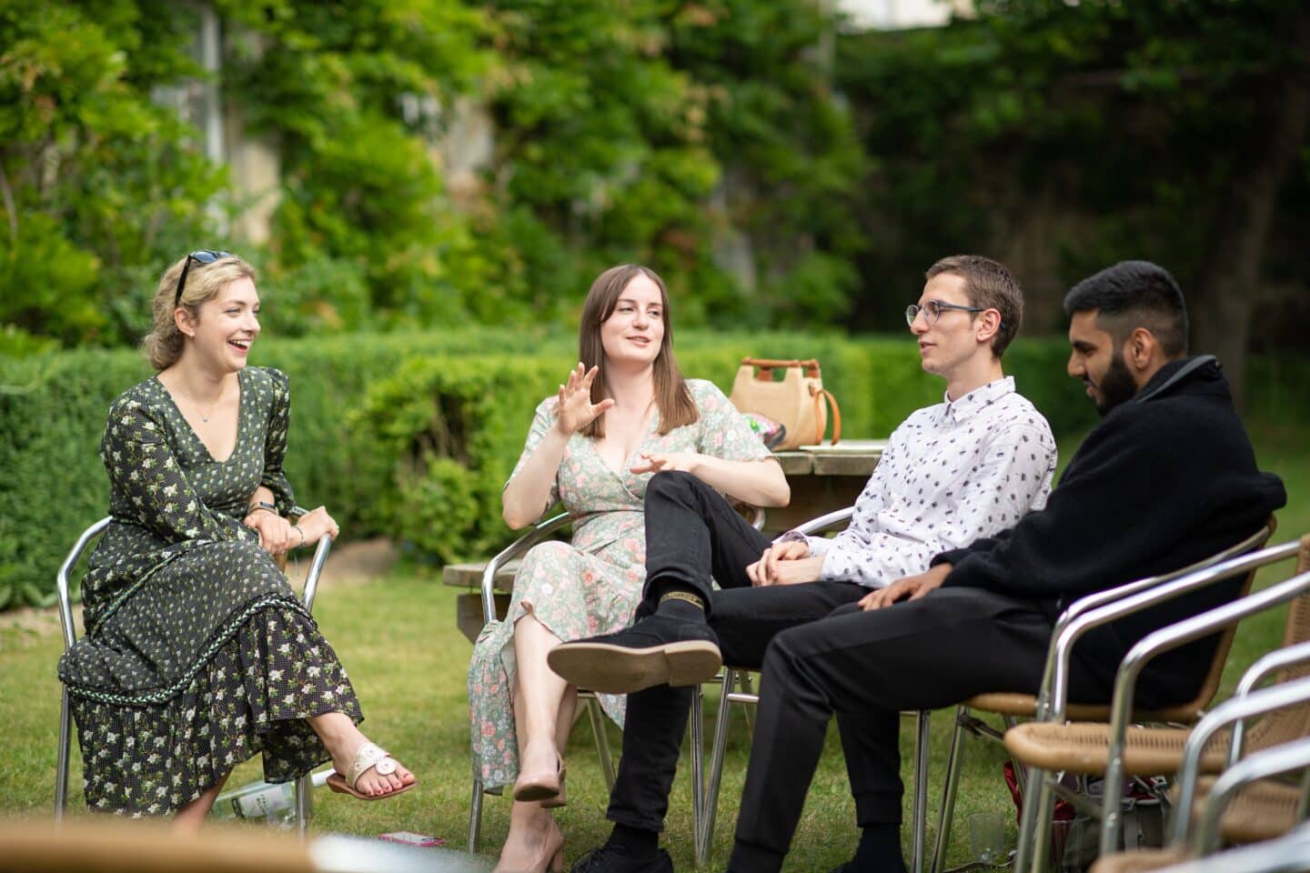 four people sitting on chairs in a garden