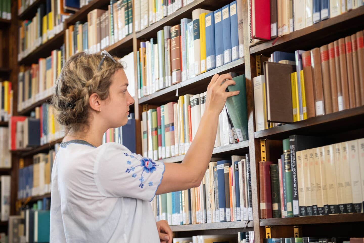 a student selecting a book from a library shelf