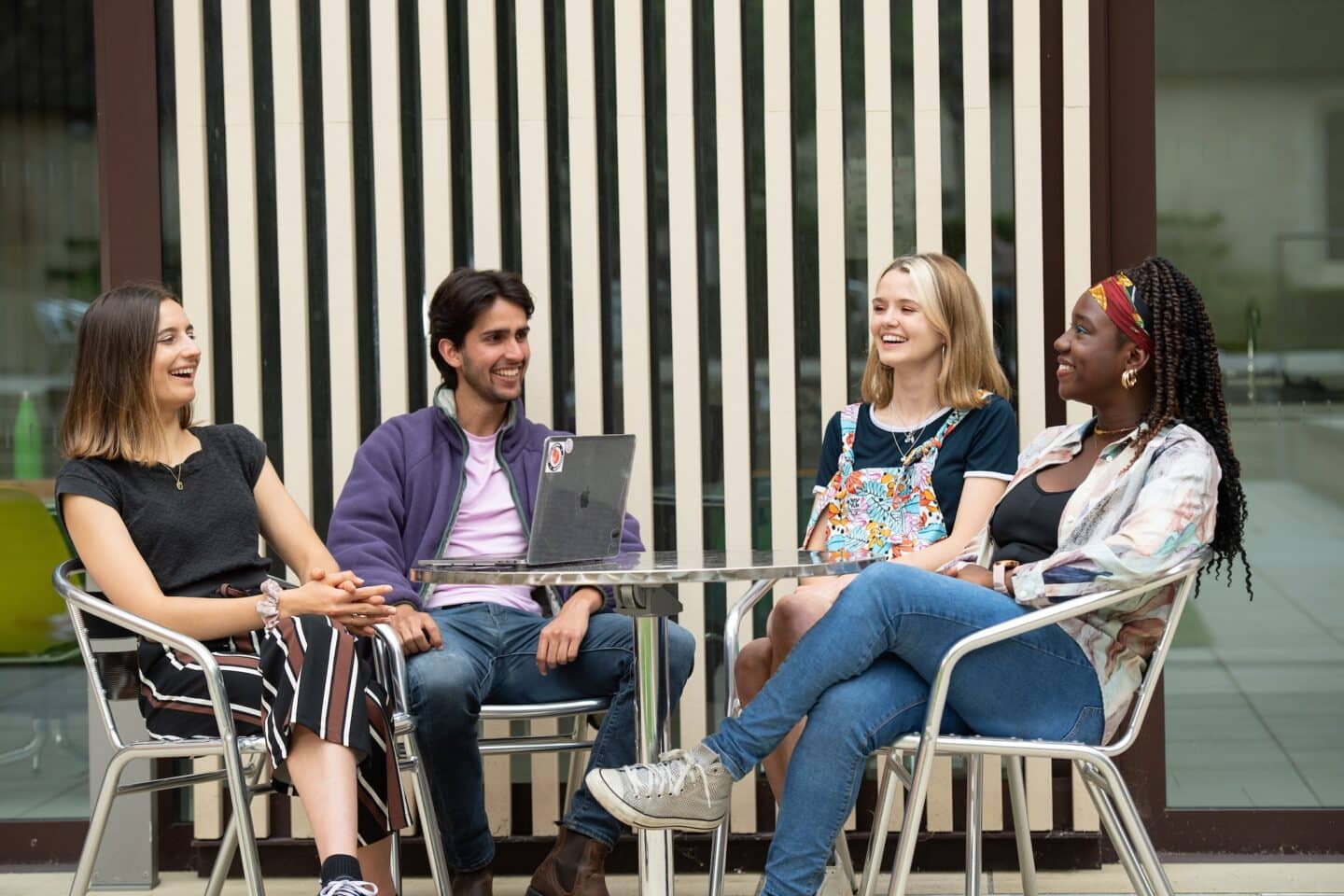 four people sitting at a table outside a building