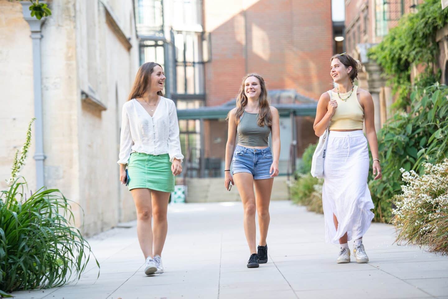 three people walking on a pavement in a garden