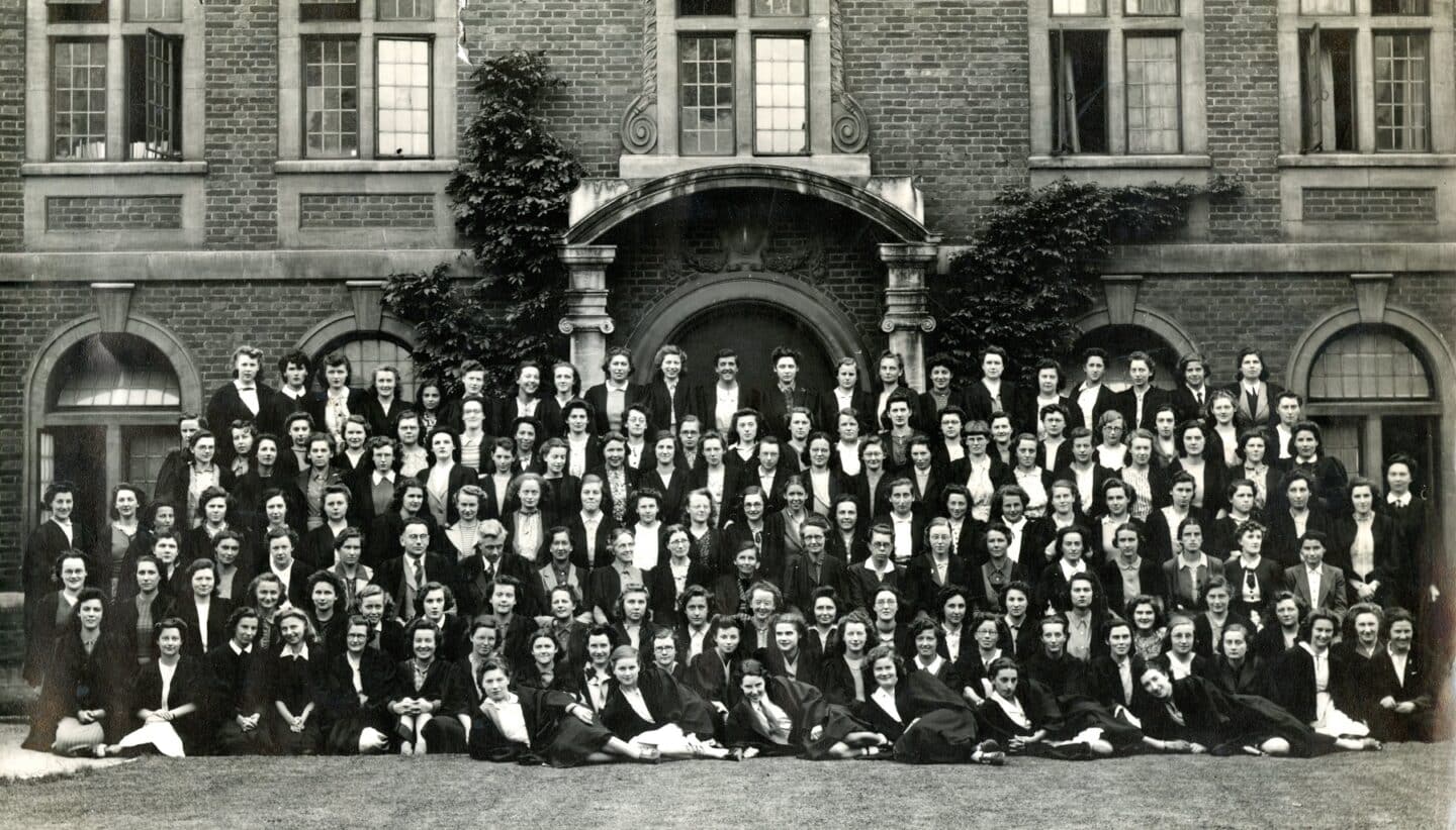 Vintage photo of a large group of women posing for a group portrait in a college quad