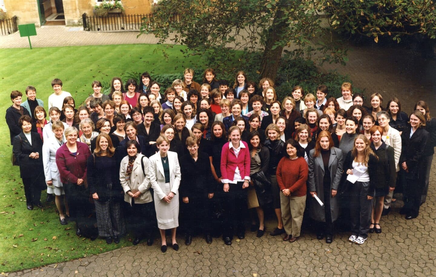 large group of women posing for a group portrait in a college quad