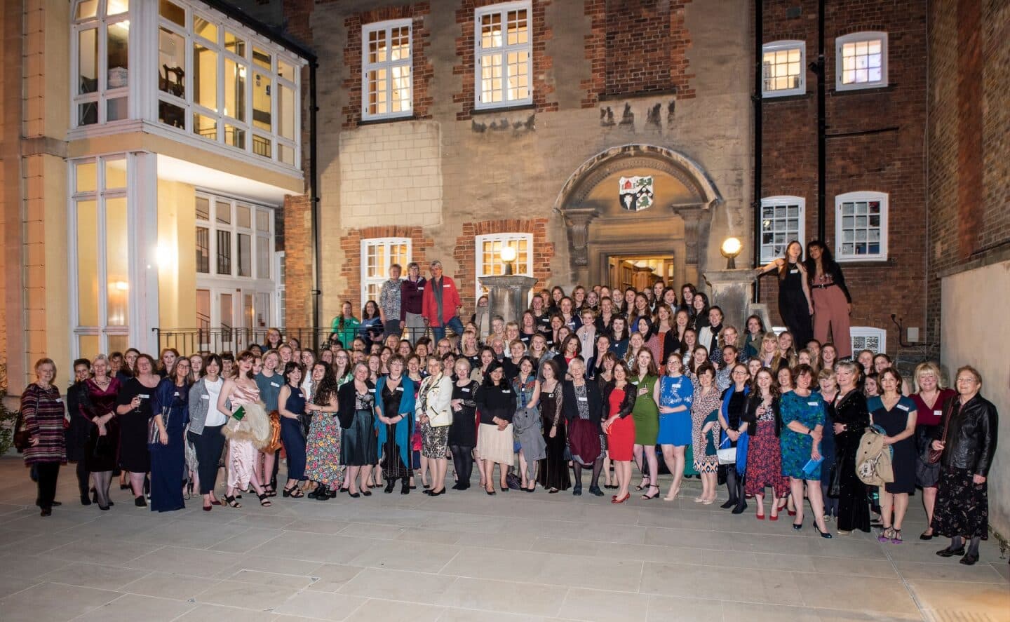 large group of women posing for a group portrait in a college quad